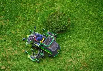 green and black ride on lawn mower on green grass field during daytime