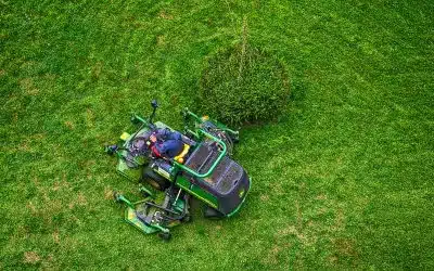 green and black ride on lawn mower on green grass field during daytime