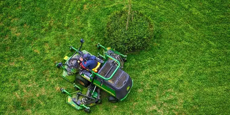 green and black ride on lawn mower on green grass field during daytime