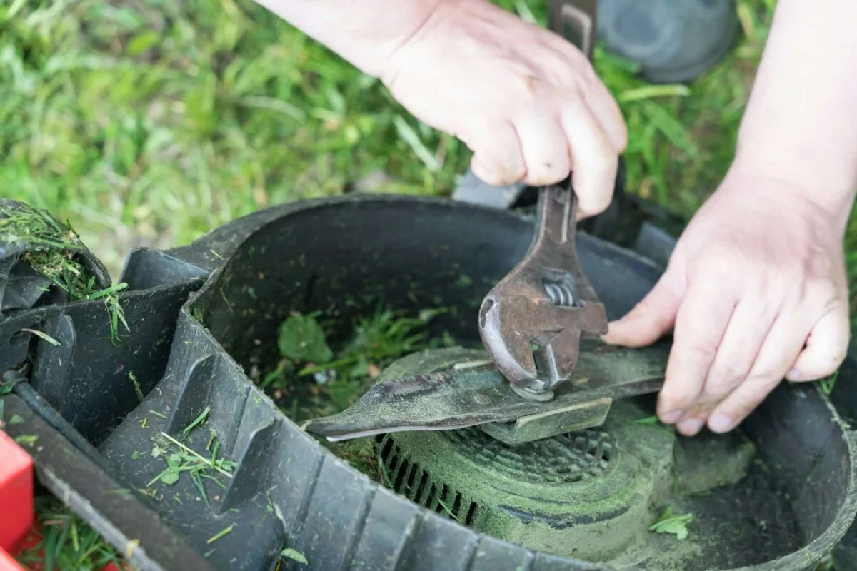 Homme réparant une tondeuse à gazon dans un jardin